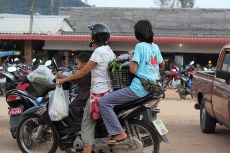 Locals shopping in Thailand, the father wearing a crash helmet. The small child withoutのeditorial素材