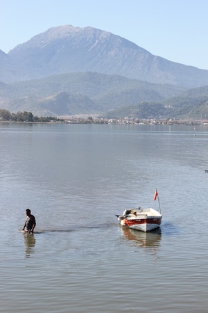 A local fisherman with his boat checking his nets at Fethiye harbor in Turkey,calis,30th may 2013のeditorial素材