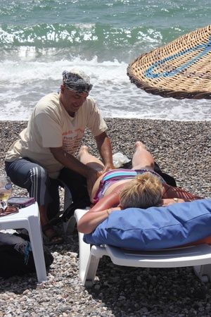 Masseur giving a full body oil massage to a beautiful mature woman on the beach at calis in Turkey on the 30th May 2013のeditorial素材