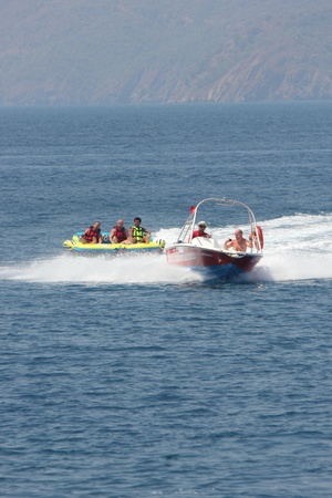 Turkey, July 2013 - Tourists having fun riding on inflatables being pulled by a speedboat
