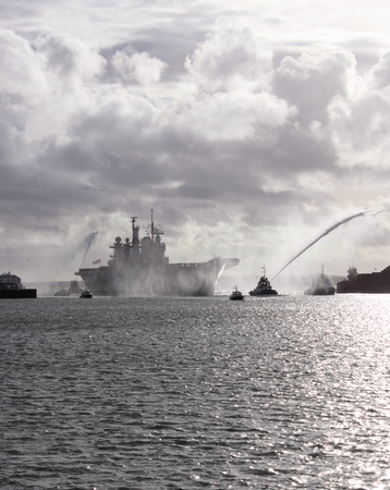  PORTSMOUTH, ENGLAND, 10TH JANUARY 2014  HMS Illustrious,the aircraft carrier returns to portsmouth after its deployment to the Philippines with a water canon salute from the tugboats, 10th january 2014の写真素材