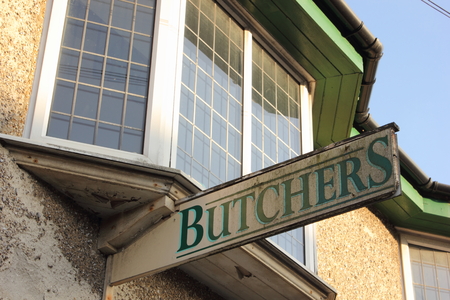 An old weathered Butchers sign hanging outside of a shop