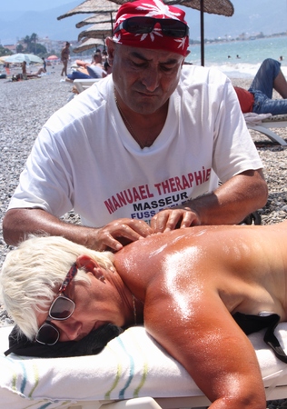 Masseur giving a full massage to a beautiful mature woman on the beach at calis in Turkey on the 19th july 2014のeditorial素材
