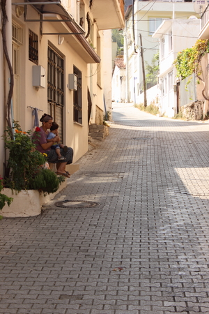 A turkish lady sitting outside her house with her child in fethiye, turkey 2014のeditorial素材