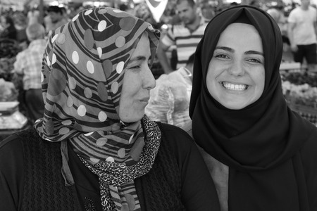 CALIS, TURKEY - 6TH AUGUST, 2017:A portrait of a young turkish girl and her mother working at a fresh fruit and vegetable produce market in Calis, Turkey, 6th august 2017のeditorial素材