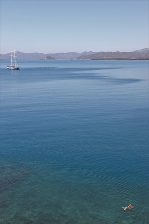28TH JULY 2017,FETHIYE,TURKEY: A yacht and a swimmer in the calm waters at calis,fethiye in turkey, 28th july 2017のeditorial素材