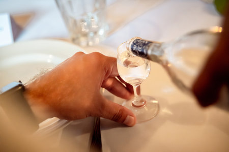 hands of a man pouring alcohol into a glass