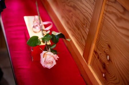 flowers bouquets bouquets and boutonnieres a rose with a ribbon lying on a red wooden bench in the churchの写真素材