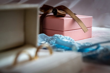 wedding rings and details a white box with wedding rings and a blue garter lying on the bed against the backdrop of a white veilの写真素材