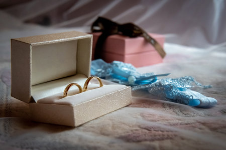 wedding rings and details a white box with wedding rings and a blue garter lying on the bed against the backdrop of a white veilの写真素材