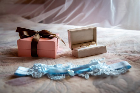 bride and groom's wardrobe and items of clothing blue bridal garter lying on the bed against the background of a blurred white veilの写真素材