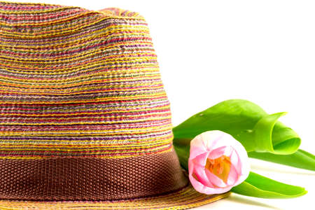 Pink tulip and colored straw hat on a white backgroundの写真素材