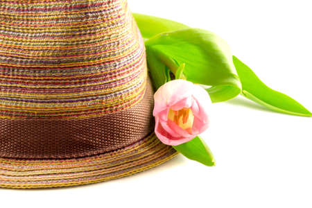 Pink tulip and colored straw hat on a white backgroundの写真素材