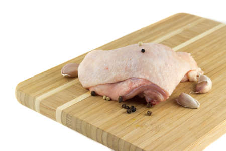 Chicken thighs on a wooden board with pepper and garlicの写真素材