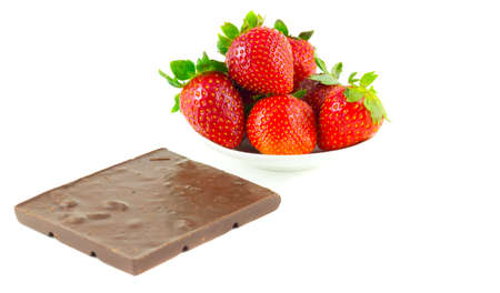 everal strawberries on a saucer and a chocolate barの写真素材