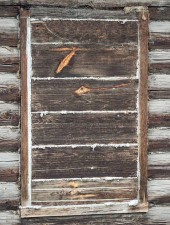Boarded-up window in an old brown log houseの写真素材