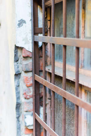 Rusty window bars on the background of an old broken wallの写真素材