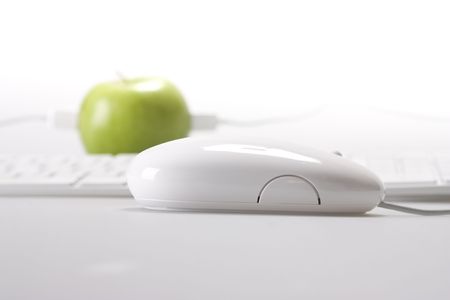 An apple on desktop whit keyboard and mouse on white backgroundの写真素材