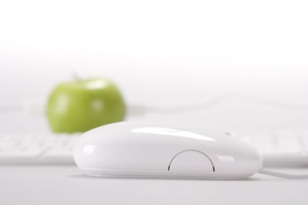 An apple on desktop whit keyboard and mouse on white backgroundの写真素材