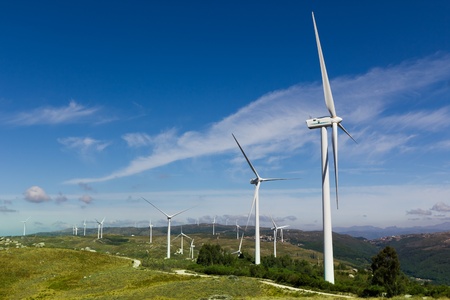 View of a wind farm with a blue sky and clouds.
