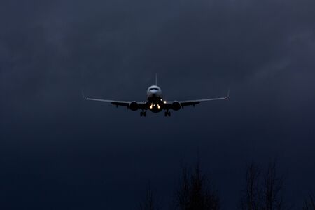 Front view of passenger airplane landing at nightの写真素材