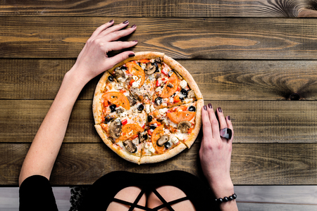 CLOSEUP Top view VERY HOT SLICED Italian Pizza with hand take a slice on wooden table with mushrooms, tomato, olives and cheese. Look as Prosciutto, Capricciosa, Funghi, Cotto HOMEMADE PIZZAの写真素材