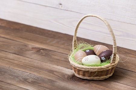 Happy easter! Beautiful Easter eggs are decorated in bed colors in a basket on a wooden background....