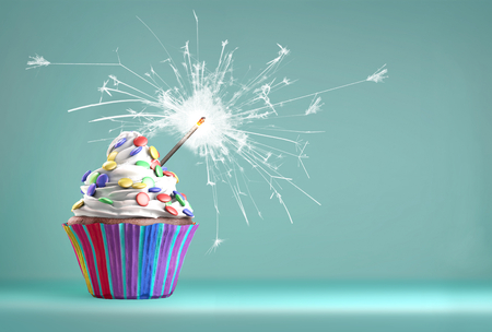 Delicious cupcake with a glittering sparkler and smarties we whipped cream. Copy space available.の写真素材