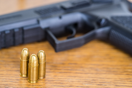 Close up view of bullets and handgun. Shallow depth of field. Pistol out of focus.