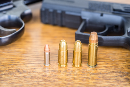 Close up view of different type of bullets and handgun. Shallow depth of field. Pistol out of focus.
