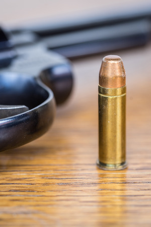Close up view of bullet and handgun. Shallow depth of field. Pistol out of focus. Vertical view.