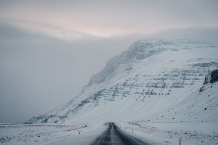 Beautiful View and winter landscape of Iceland's golden circle road during the sunset with the snow-capped mountain as a background and the road asphalt as a foreground.の写真素材