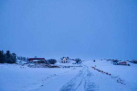 Late evening shot of remote farm surrounded with snow in winter, Iceland. Cold winter evening in Icelandic countryside.の写真素材