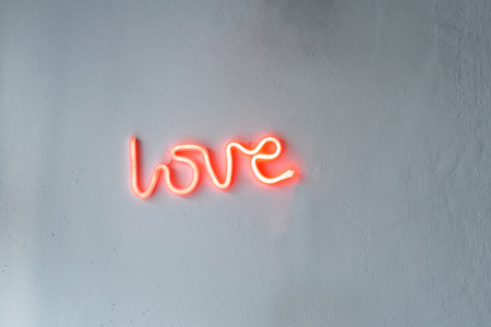 Red Neon Love SIgn on a white wall.