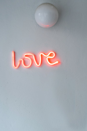 Red Neon Love SIgn on a white wall. Selective focus.の写真素材