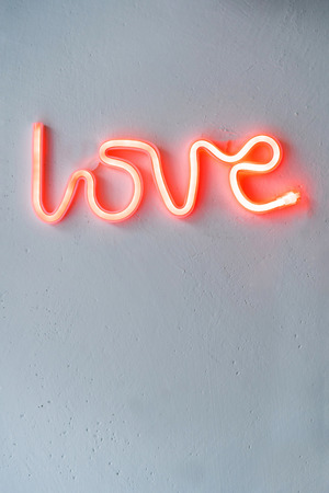 Red Neon Love SIgn on a white wall. Selective focus.の写真素材