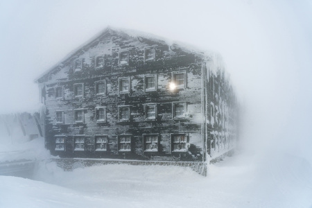 Detail view of mountain cabin in a misty weather. Foggy weather in a snow covered landscape.の写真素材