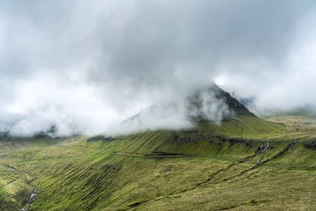 Spectacular views of the scenic fjords on the Faroe Islands with cloud-covered mountains.