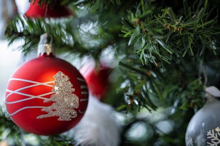 Christmas background. Detail view of red and silver baubles and festive decorations hanging on a green christmas tree.の写真素材