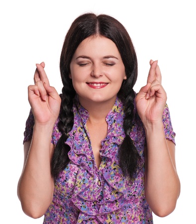 Portrait of worried young woman with crossed fingers on white backgroundの写真素材
