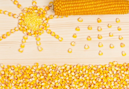 Abstract picture from grains of crude corn on a wooden surface