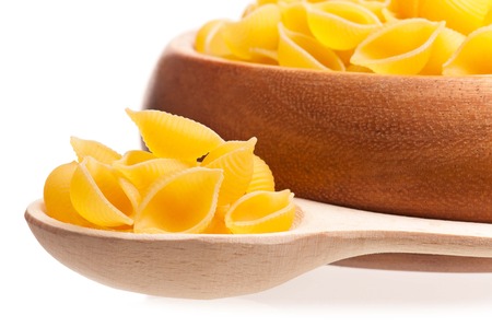 Raw macaroni in the wooden spoon over white 