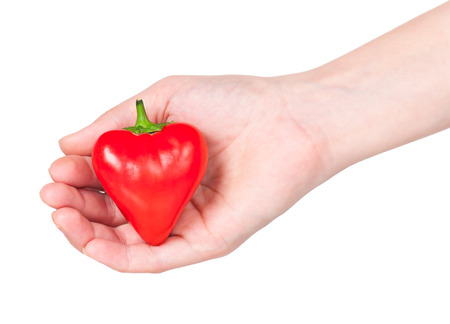 Raw red pepper in the form of heart in the hand isolated over white backgroundの写真素材