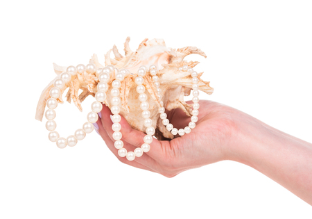 Young female hand with cockleshell and pearls isolated over white backgroundの写真素材