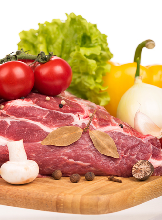 Raw pork with spices and vegetables on the chopping board over white backgroundの写真素材