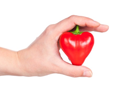 Raw red pepper in the form of heart in the hand isolated over white backgroundの写真素材