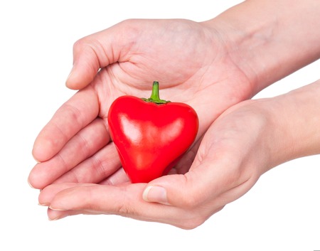 Raw red pepper in the form of heart in the hand isolated over white backgroundの写真素材