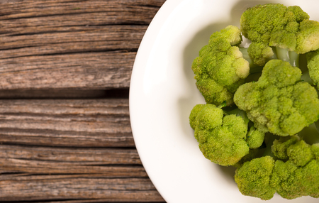 Boiled green broccoli on the plate over old wooden background with empty space for your textの写真素材