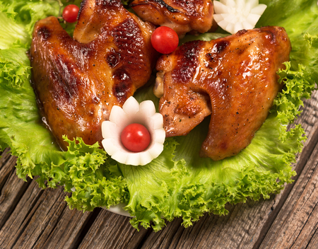 Baked chicken wings with frsh vegetables over old wooden backgroundの写真素材
