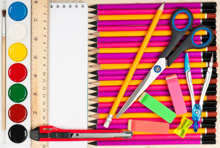 Colorful pencils with notepad and school accessories over wooden surfaceの写真素材